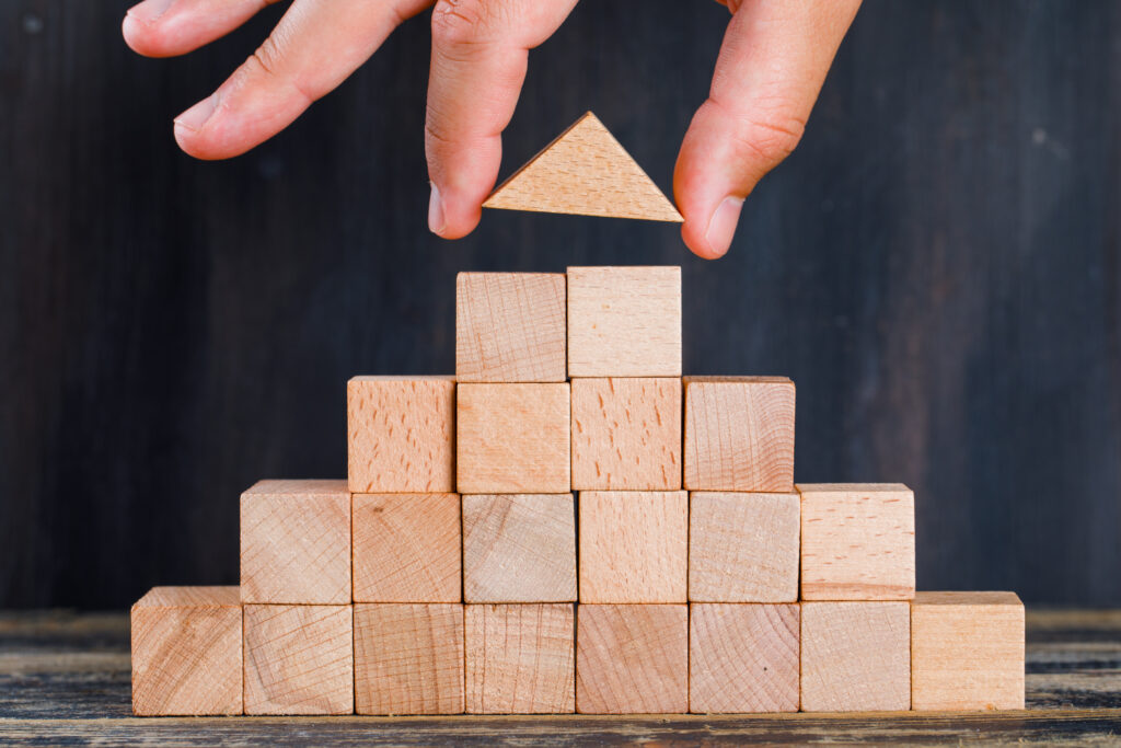 Person building a pyramid using wooden blocks.6